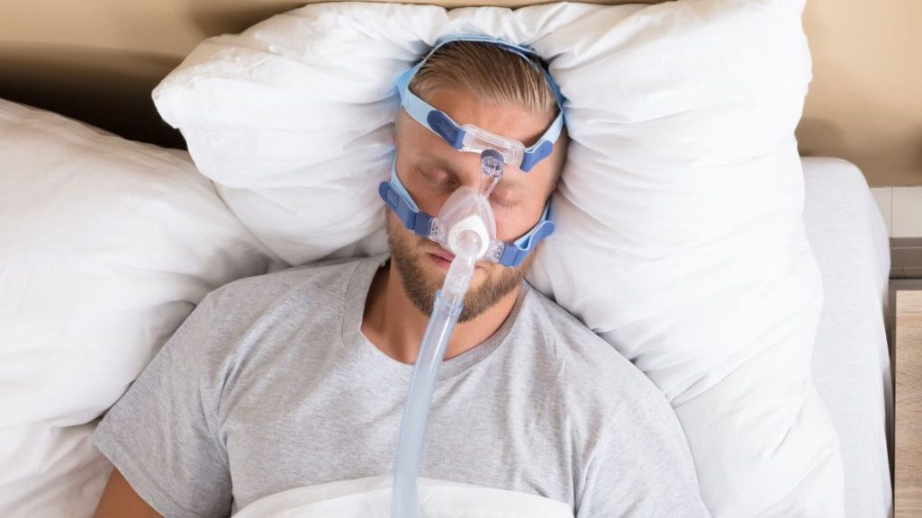 Um homem com apneia do sono dormindo enquanto usa um dispositivo CPAP