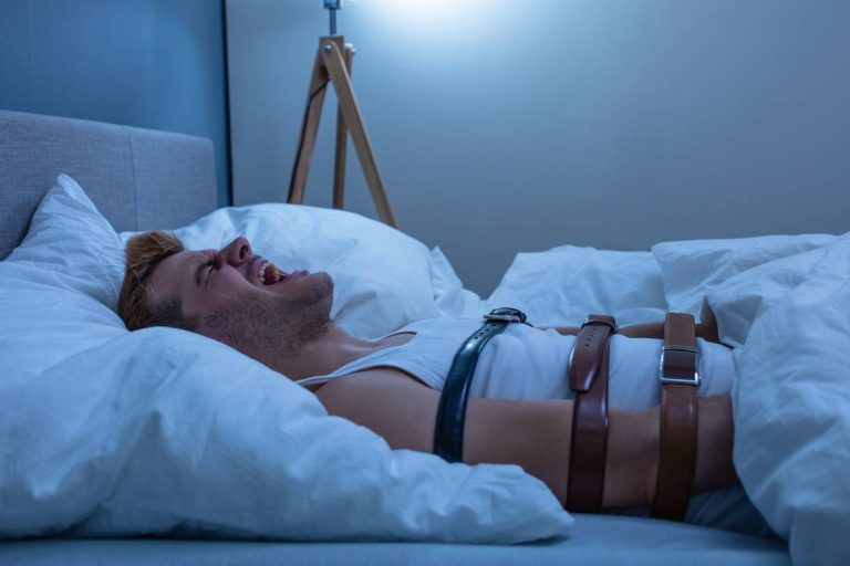 homem deitado na cama amarrado por sintos simbolizando alguém se sentindo desesperado durante um episódio de paralisia do sono